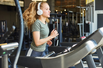 Fototapeta premium Girl in headphones running on the treadmill.