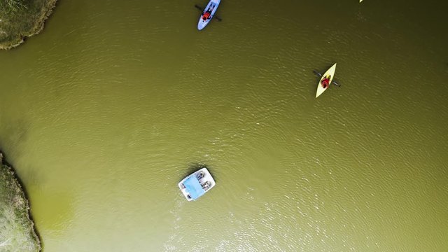 Aerial Top View, People in kayaks, canoe, and paddleboat in green lake
