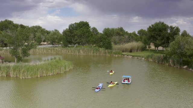 People kayaks, canoe, and paddleboat on green lake, Static Aerial Shot