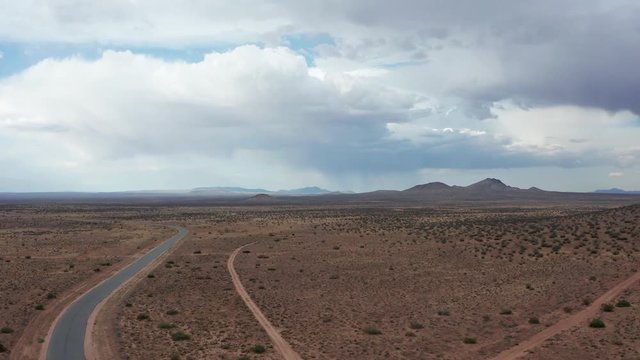 Flying over asphalt and dirt roads in Mojave Desert on cloudy day