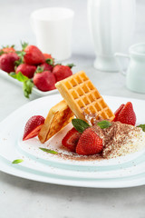 Belgian waffles with strawberries and cream, mint and chocolate chips.