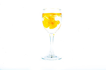 Orange food coloring diffuse in water inside wine glass with empty copyspace area for slogan or advertising text message, over isolated white background.