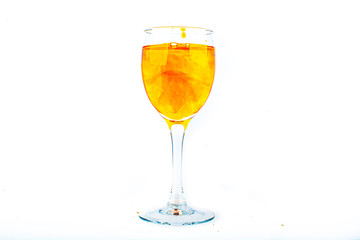 Orange food coloring diffuse in water inside wine glass with empty copyspace area for slogan or advertising text message, over isolated white background.