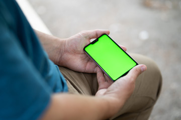 close up handsome man use left hand typing mobile phones and touch screen working with app devices in park