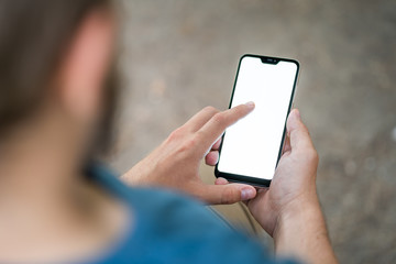 Young man sitting in the park and texting a message