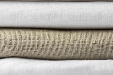 Stack of white and beige pure organic cotton and linen folded fabric. Clothing laundry home textile...