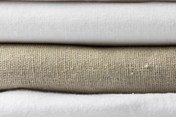 Stack of white and beige pure organic cotton and linen folded fabric. Clothing laundry home textile...