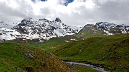 Fototapeta na wymiar Panorama view of a stream at the feet of snowy mountains