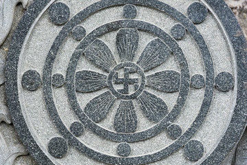 Stone carved radial design with Buddhist swastika symbol at the centre.