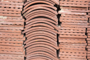 Terracotta roof tiles stacked ready for use with a symmetrical pattern.