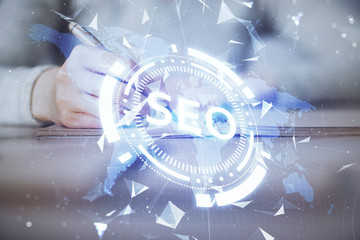 Multi exposure of woman's hands making notes with SEO icon. Concept of Search engine optimization