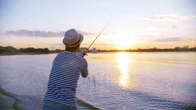 A man in panama on fishing - a man throws a fishing rod in the river - sunset