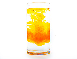 Orange food coloring diffuse in water inside tall glass with empty copyspace area for slogan or advertising text message, over isolated white background.