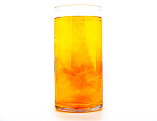 Orange food coloring diffuse in water inside tall glass with empty copyspace area for slogan or advertising text message, over isolated white background.