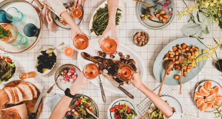 Family, friends gathering dinner. Flat-lay of peoples hands clinking with glasses of rose wine over...