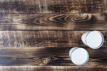 two glasses of milk on wooden background, top view