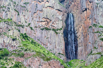 Summer landscape with mountain waterfall between two rocks
