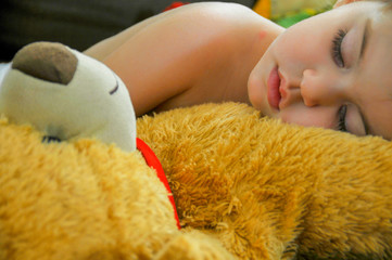Isolated close up of a beautiful  young girl napping with her teddy bear