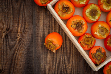 Ripe orange persimmon fruit on brown wooden table. Organic persimmon fruit  at market. Persimmons background with copy space, text place 
