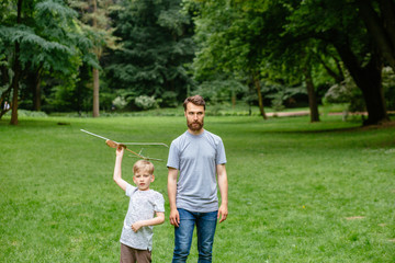 Dad and son together launch model airplane outdoors, both man and boy are looking cheerfully at plane. Father and son spending good time together, family relationships concept. Full leight