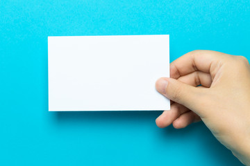 Hand holding up a note card on a blue background