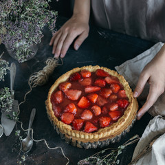 On the dark table strawberry pie on sand dough.