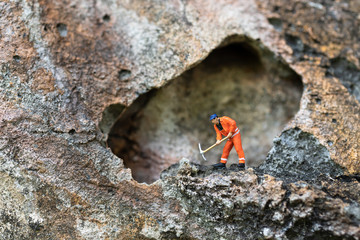 Miniature people: Men in uniform are using shovels to drill stones. Image use for drilling business.