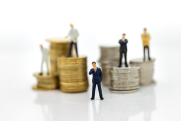 Miniature people:  Businessman standing on the stack of coins. Image use for business concept.