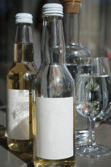 Side of a bottle with a white label. One half full and the other one full. with water glasses in the background.