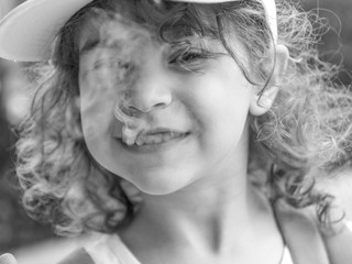  Isolated close up portrait of a beautiful five year old girl in black and white with smoke coming out of her mouth