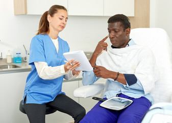 Obraz premium Cosmetician with papers talking to man before procedure in medical esthetic office
