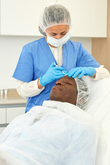 Doctor is doing injection to man patient in skin of face in estetic clinic