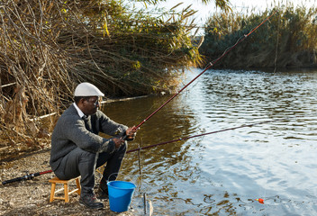 Positive fisherman sitting near river
