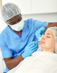 Woman client and doctor during beauty facial injections in medical esthetic office