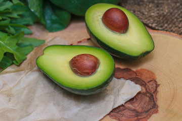 Avocado on a wooden Board with the spinach leaves. Fresh avocado sliced on vintage wooden background closeup. Ripe green avocado fruit on a wooden Board. Healthy food concept, organic food, vegetarian