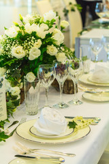Wedding party dinner table setting with tableware and silverware and glasses set and Candlestick and flower in restaurant.