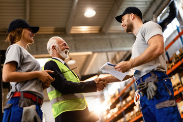 Fototapeta na wymiar Below view of industrial workers greeting senior businessman in a warehouse.