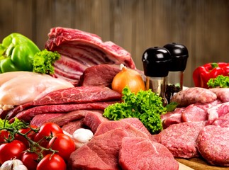 Fresh raw meat with vegetables on brown wooden table at wooden background