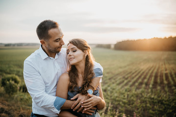 couple in love in a field at sunset in the summer smiling and happily hugging. engagement concept, weddings in nature.