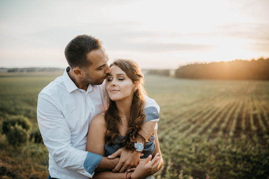couple in love in a field at sunset in the summer smiling and happily hugging. engagement concept, weddings in nature.