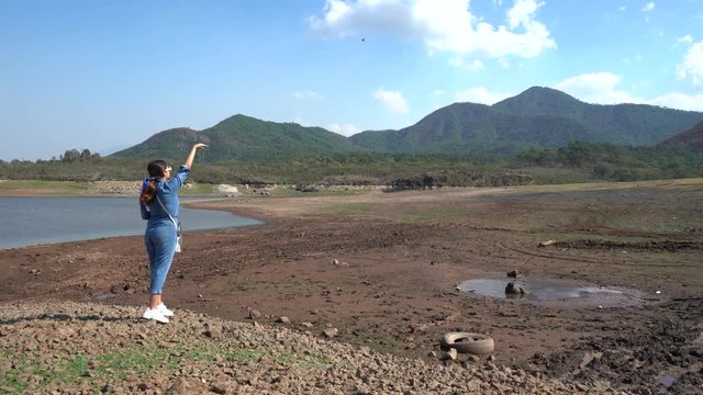 La joven est&aacute; lanzando piedras al charco de agua.
