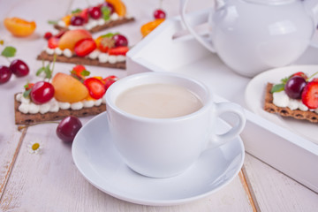 Fototapeta na wymiar Cup of tea and crisp bread with creme cheese, fruit and berries