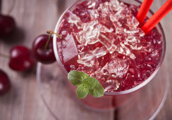 Glass with fresh homemade cherry sweet iced tea or cocktail, lemonade with mint. Refreshing cold drink. Summer party.