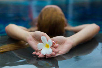 Blonde model in pool with flowers