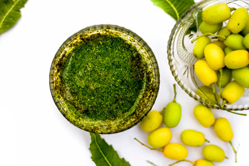 Neem paste or nim paste in a glass bowl isolated on white along with neem fruit in another bowl and...