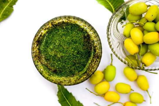 Neem paste or nim paste in a glass bowl isolated on white along with neem fruit in another bowl and some leaves also in it.