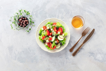 Greek salad. A plate of fresh salad with lettuce, feta cheese, tomatoes, cucumbers, onions and olives, shot from the top with white wine and a place for text