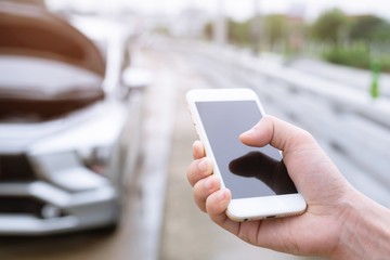 close up businessman hand using a mobile smart phone call a car mechanic ask for help assistance because car broken.