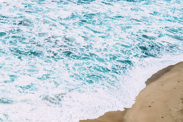 White and blue waves against a sandy beach