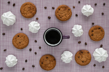 Delicate layout on a woven napkin with oatmeal cookies, a cup, coffee beans and white marshmallow